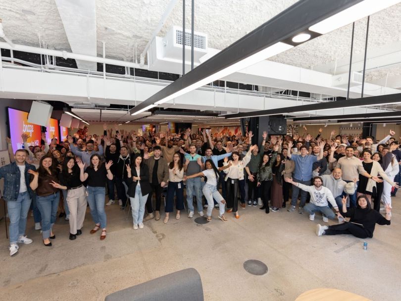 Braze team members make silly poses while gathered together for a large group photo in the company’s office.