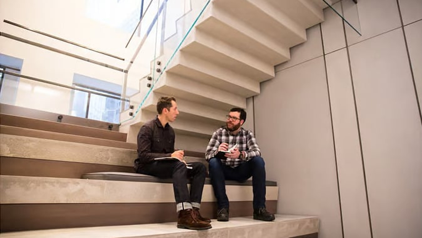 Two employees chat in the office common area.